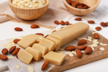 Wall Mural - Cutting board with tasty marzipan, almond nuts and flakes on light table