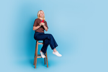 Canvas Print - Photo of lovely pretty cheerful woman wear stylish clothes sitting wooden chair look empty space isolated on blue color background