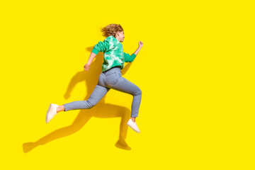 Wall Mural - Full length photo of adorable lovely girl wear tie dye sweatshirt jumping high running empty space isolated yellow color background