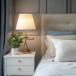 © Nath studio - Cozy bedroom interior nightstand with lamp and home plant near bed. Close up shot of bed headboard with pillows and bedside table.