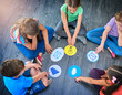 © Koegelenberg Coop/peopleimages.com - Children, students and playing game on floor with communication icons, decision making and learning. Diversity, people and problem solving with educational activity, solution or knowledge on top view