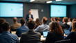 © cabado - Modern conference room filled with attentive diverse audience listening focused on blurred professional speaker presenter man or college teacher presenting with projection screen in distance at front.