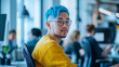 © Dirk - Gay gen z asian man with blue hair working in an office with other collegues, open office landscape. Acceptance of diverse people, multiracial colleagues in an office. Inclusive theme.