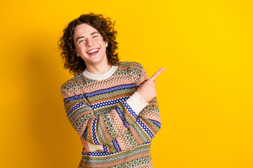 Poster - Photo of satisfied guy with wavy hairdo dressed ornament sweater indicating at offer empty space isolated on yellow color background