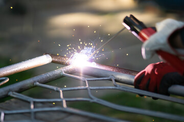 Close up of a welder welding metal frame outdoors