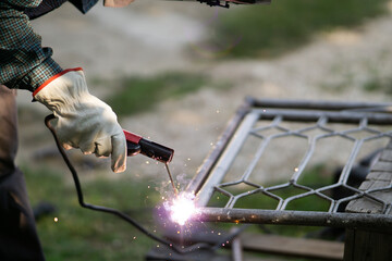 Close up of a welder welding metal frame outdoors