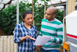 © JackF - Latino man and woman farmers signing papers and communicating near car at glasshouse