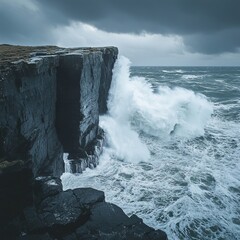 Wall Mural - Dramatic waves crashing against a rugged cliff face on a stormy day.