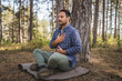 © Miljan Živković - Adult man camper practice meditation and breath exercise in front tree