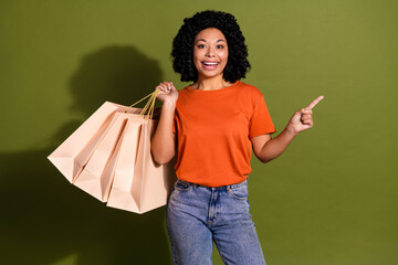 Portrait of nice young woman bags indicate finger empty space wear orange t-shirt isolated on khaki color background