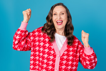 Wall Mural - Photo portrait of lovely senior lady winning raise fists dressed stylish pink print garment isolated on blue color background