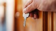 © LifeMedia - A person is holding a metal key and is about to insert it into the keyhole of a wooden door, implying the action of unlocking or locking the door.