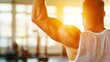 © LifeMedia - A man wearing a sleeveless shirt works out by lifting weights in a brightly lit gym with large windows, sunlight streaming in, highlighting fitness and strength.