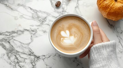 Sticker - Woman's hand holding a cup of coffee with latte art on a marble table with a pumpkin and coffee beans.