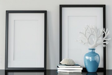 Two black empty frames mockup on a black shelf or desk with a blue vase, coral, and books. Minimalistic interior design.