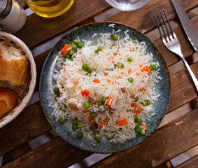 Appetizing rice with meat, carrots and peas served on plate