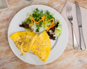 Wall Mural - Appetizing fluffy omelet of beaten eggs seasoned with herbs served with mixed fresh greens..