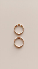 two gold wedding bands on beige background