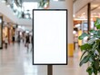 © Pongsatorn - Blank advertising display in a shopping mall, with blurred shoppers in background.
