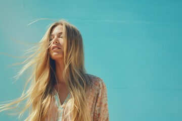 Poster - A woman with long blonde hair is standing in front of a blue wall