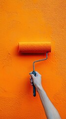 Close up hand painting with paint roller on the wall, Orange color