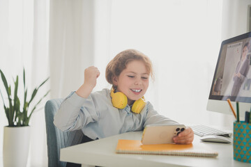 Poster - Photo of funny positive glad adorable girl schoolkid sitting chair hand fist yes modern technology daylight indoors