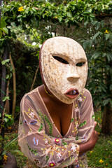 A young black woman wearing a traditional antique mask