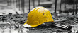 © Komkrit - A yellow hard hat lying on a black and white construction site next to monochrome tools
