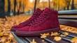 © fotogurme - Dark red high-top sneakers with suede texture and thick soles placed on a park bench background casual fall adventure