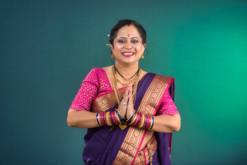 Portrait of a traditional Indian woman in a greeting pose to Namaste hands. Indian woman in traditional saree.