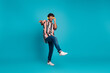 © deagreez - Full length photo of attractive funny guy wear striped shirt headphones dancing emtpy space isolated blue color background