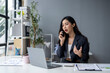 © apichat - A woman is talking on her cell phone in a business setting