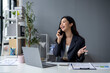 © apichat - A woman is talking on her cell phone while sitting at a desk