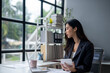 © apichat - A woman in a business suit is sitting at a desk with a laptop and tablet