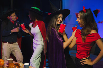 Wall Mural - Dinner and group of people celebrating together at Halloween party. Friends are happy and celebrating with food, wine and friendship of love and cheers of champagne at the event.