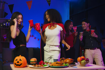 Wall Mural - Dinner and group of people celebrating together at Halloween party. Friends are happy and celebrating with food, wine and friendship of love and cheers of champagne at the event.