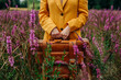 © VISTA by Westend61 - Hands of woman holding suitcase and standing amidst pink flowers in field