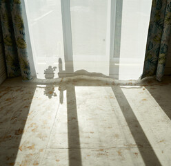 background. sunlight falls on the floor of the room through a window covered with a curtain