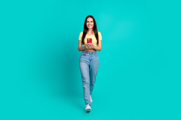 Poster - Full size photo of nice young woman walk use phone wear top isolated on teal color background