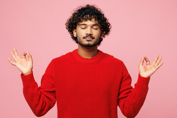 Wall Mural - Young spiritual Indian man he wear red sweater casual clothes hold spreading hands in yoga om aum gesture relax meditate try to calm down isolated on plain pastel pink background. Lifestyle concept.