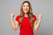 © ViDi Studio - Young overjoyed fun excited happy woman she wearing red t-shirt casual clothes do winner gesture celebrate clenching fists say yes isolated on plain grey background studio portrait. Lifestyle concept.