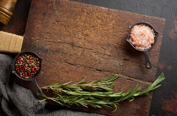 Culinary composition with kitchen utensils and seasonings including Himalayan salt, colorful peppers, fresh rosemary on wooden board. Top view