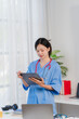 © Kritdanai - Focused Physician Reviewing Charts: A dedicated female doctor, dressed in scrubs with a stethoscope, meticulously reviews patient charts on a tablet.  The image conveys professionalism, attentiveness.