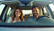 © Ali Hamza Tullah - Front portrait of happy couple sitting in luxury car, man and woman enjoying road trip or buying new car, smiling at camera, windshield view