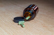 © Angel - Open pill bottle on a table with several pills on the table.