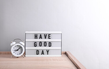 Light box with the text have good day with alarm clock on gray background