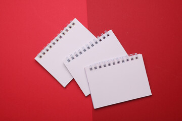 Poster - Group of white blank spiral notebooks on red background