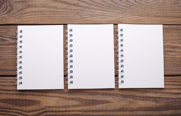 Wall Mural - Group of white blank spiral notebooks on wooden background