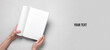 © splitov27 - Women's hands hold magazine or catalog with an open blank white page on a gray background. Template for design, mockup, copy space