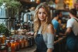 © Nova Widiawati - A young woman with long blonde hair smiles at the camera while standing behind a counter with jars of preserves in a cafe setting.